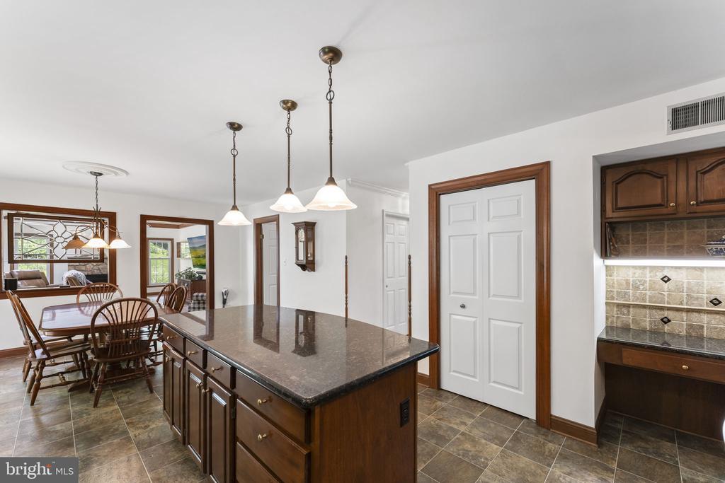 Kitchen with a large stone island, pendant lights, and an adjoining dining area with a wood table.
