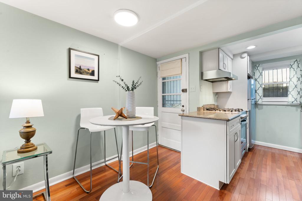 Kitchen and dining nook with hardwood floors, white cabinetry, and a round table.
