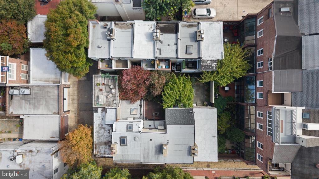 Aerial view of flat-roofed residential buildings surrounding a tree-filled courtyard.
