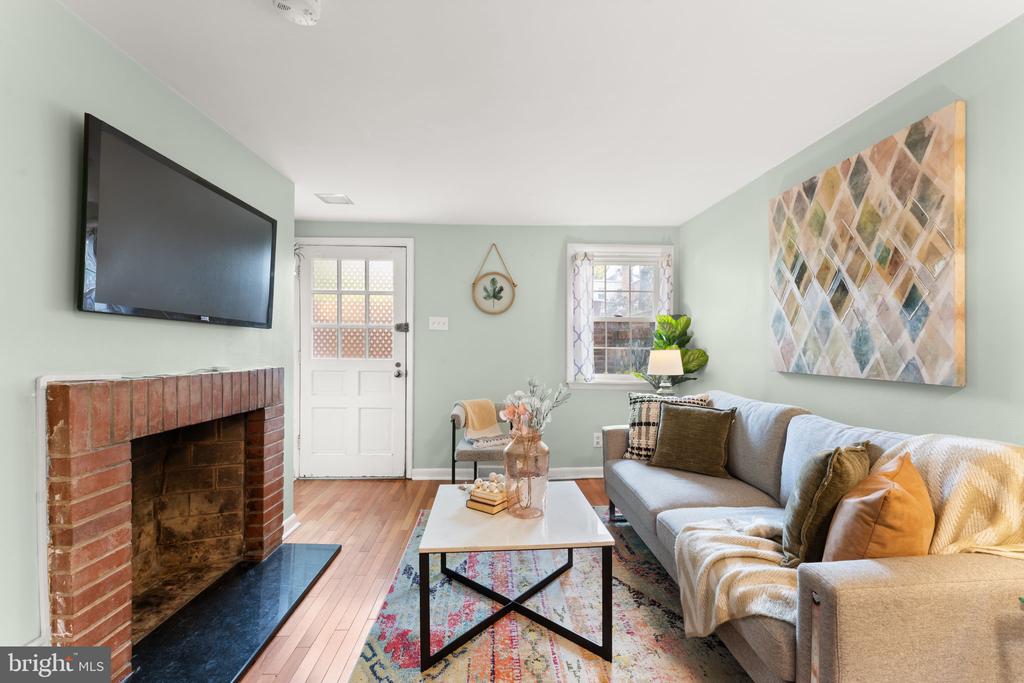 Furnished living room with a brick fireplace, wall-mounted TV, and gray sofa.