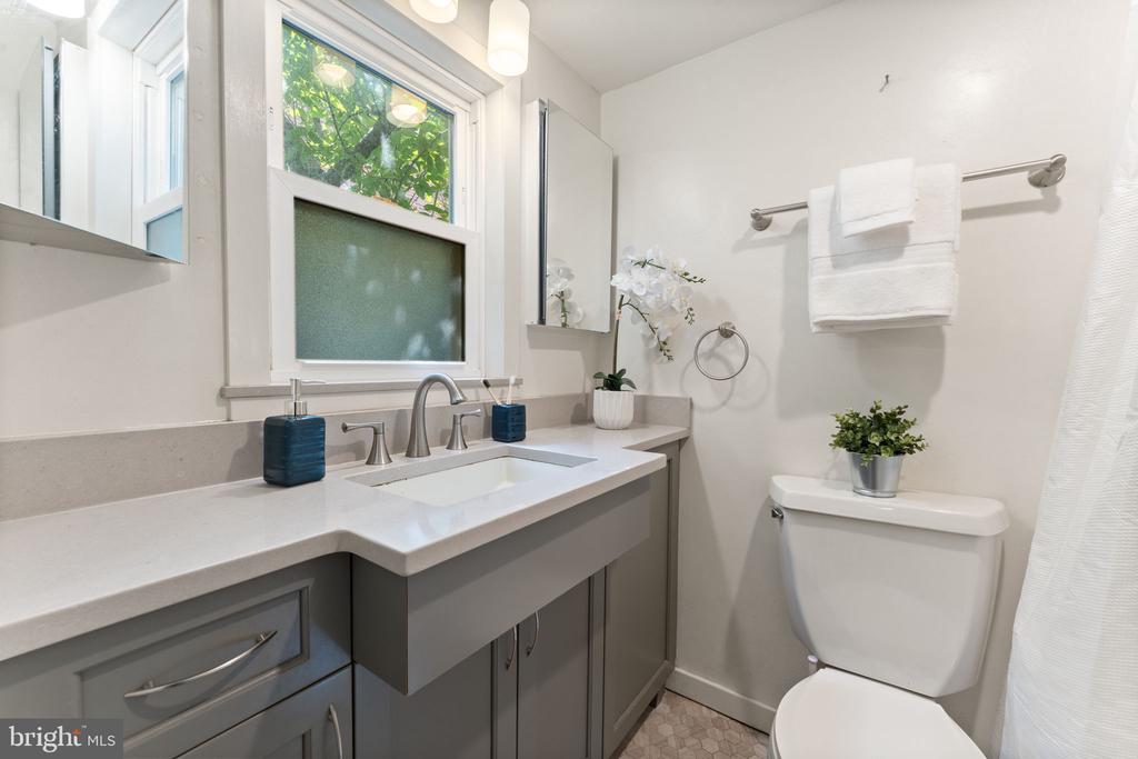 Bathroom with a gray vanity, white countertop, frosted window, and toilet.