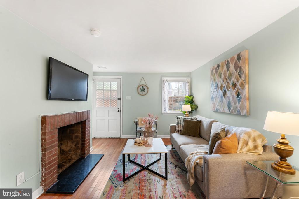Staged living room with a brick fireplace, wall-mounted television, and gray sectional sofa.