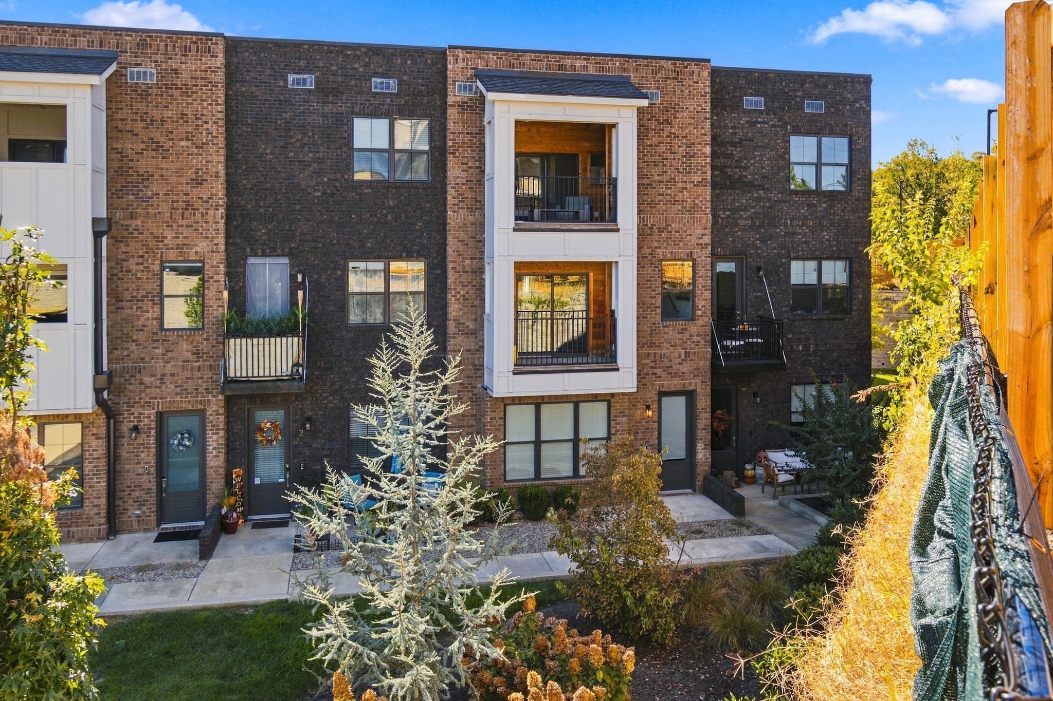 Brick residence with stacked balconies and landscaped courtyard paths.