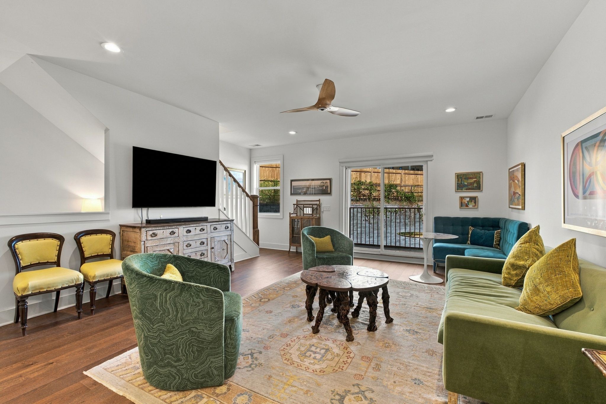 Living room with green and teal seating, a patterned rug, and sliding doors to a balcony.