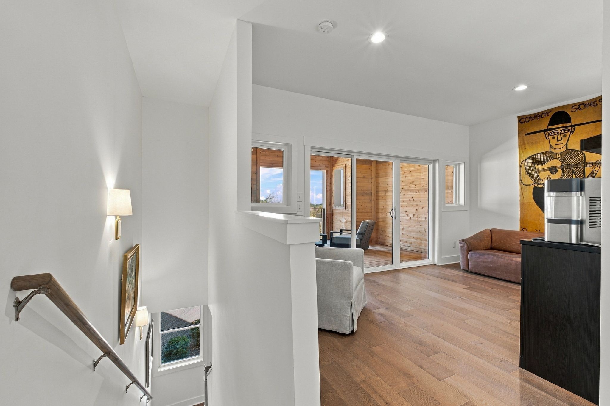 Living room with wood floors, sliding doors to a covered patio, and cowboy artwork.