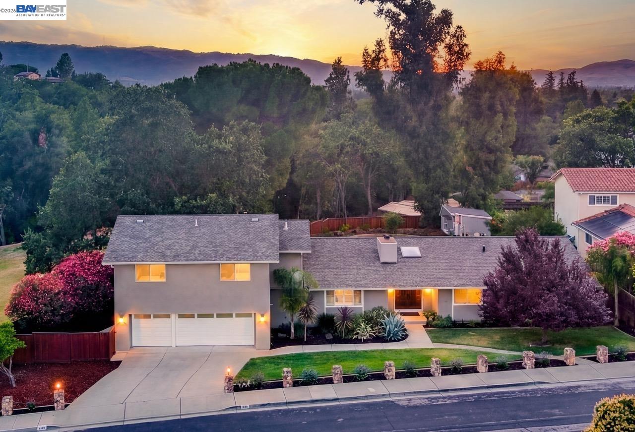 Two-story suburban home with a double garage and landscaped yard at sunset, viewed from above.