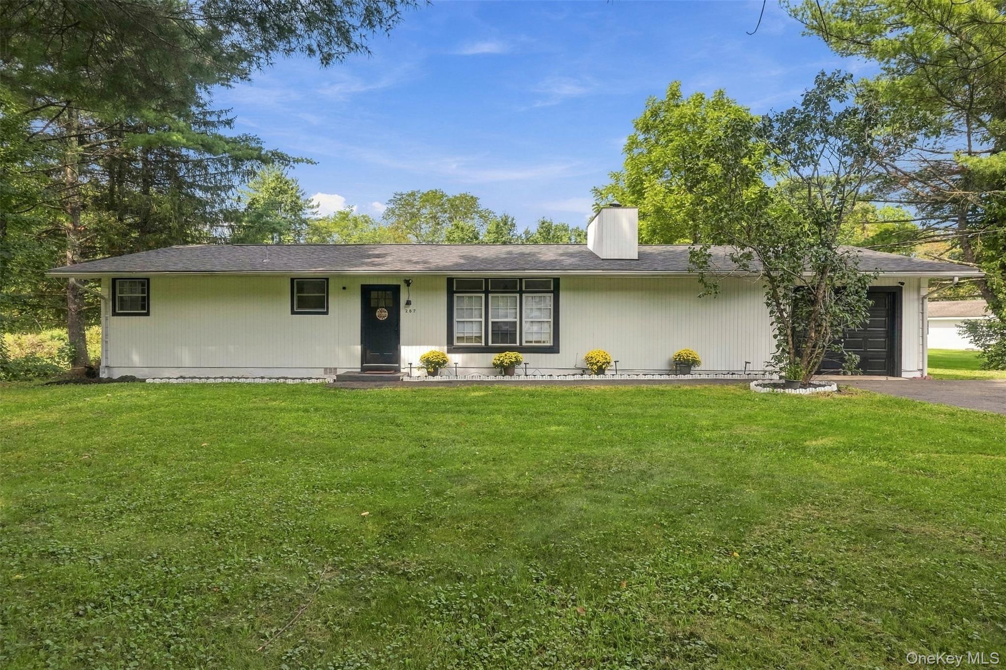 Single-story white house with a broad lawn, mature trees, and an attached garage.