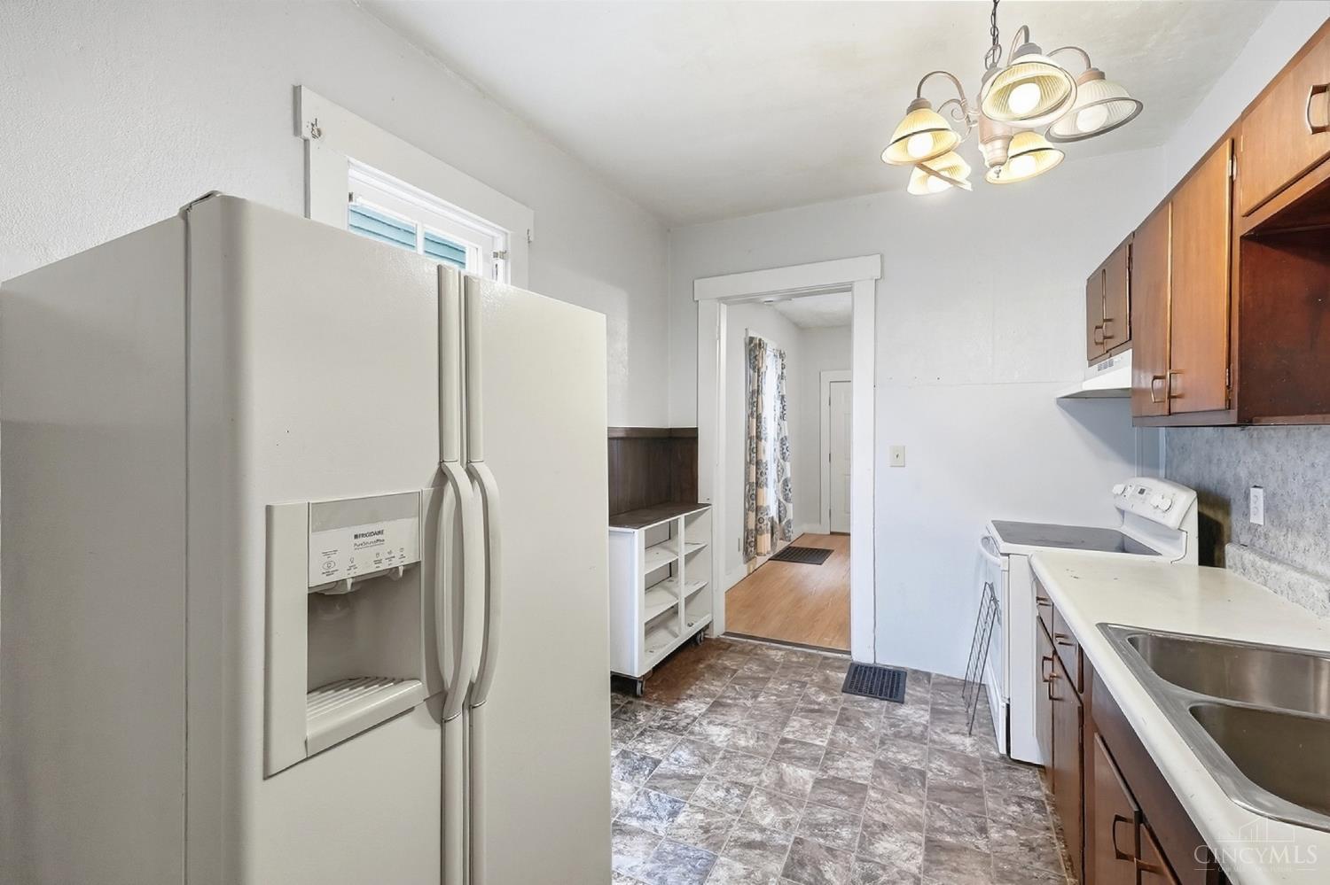 Kitchen with a large white refrigerator, wood cabinets, and patterned flooring.