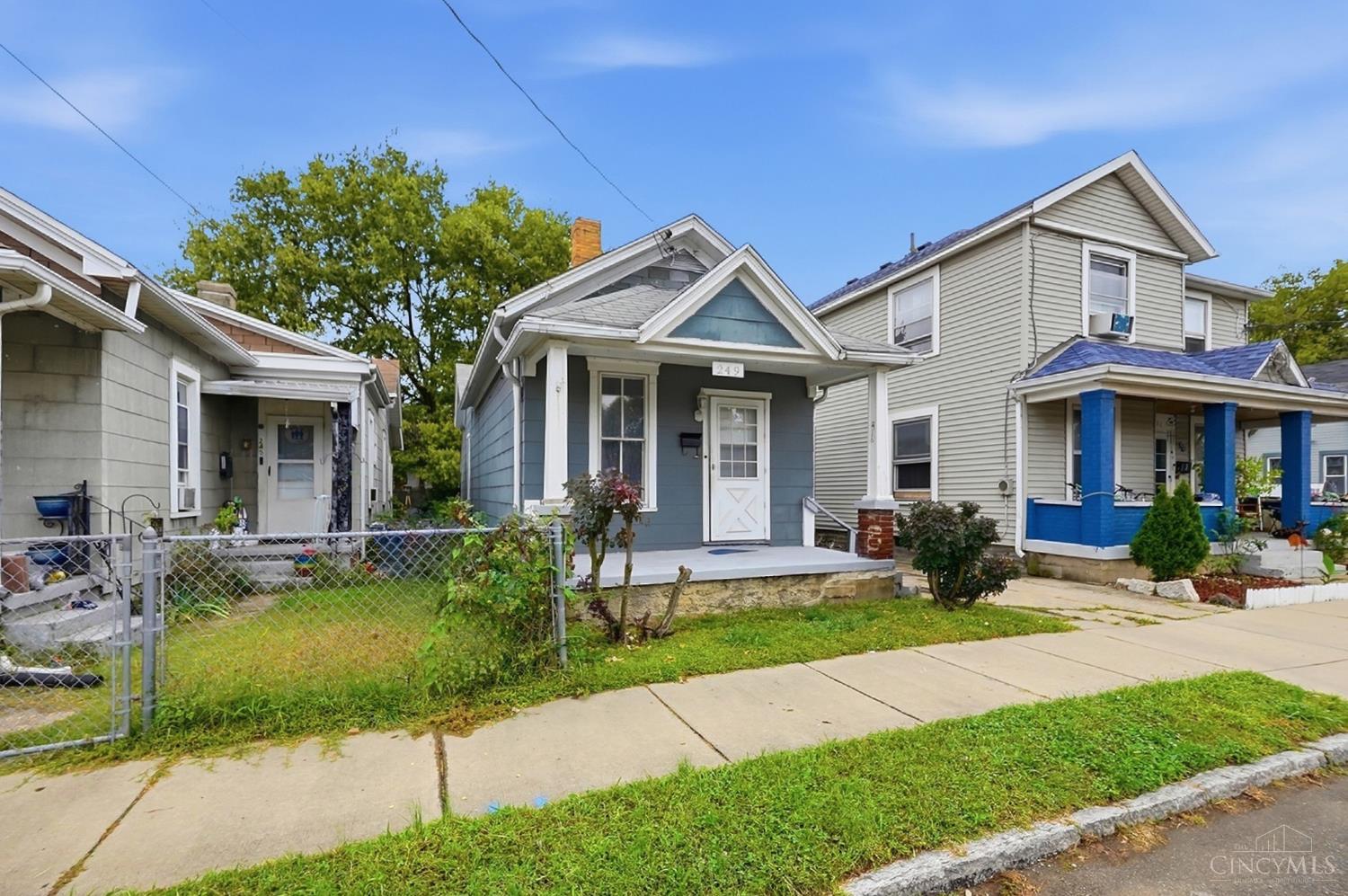 Blue-gray single-story house with a covered porch, white trim, and fenced front yard.