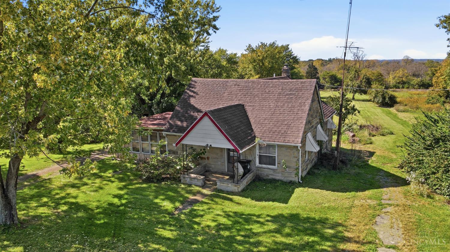 Stone house with a red-trimmed front gable, surrounded by a broad lawn and mature trees.