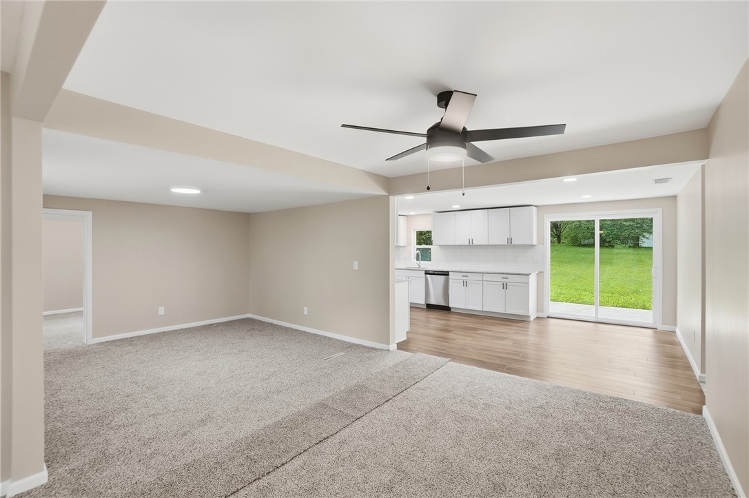 Carpeted living area opens to a bright white kitchen with sliding doors to the lawn.