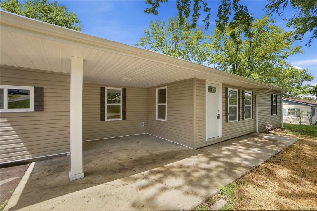 Home’s rear exterior with a broad covered concrete patio and tan siding.