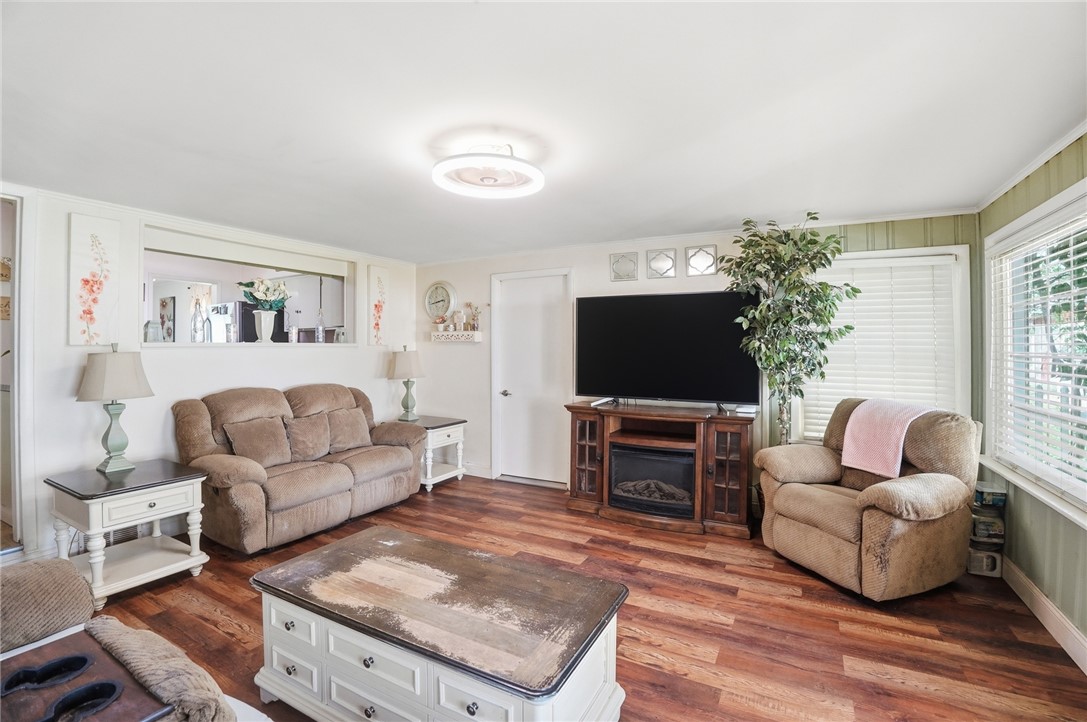Living room with brown seating, a television above a fireplace insert, and reddish wood flooring.