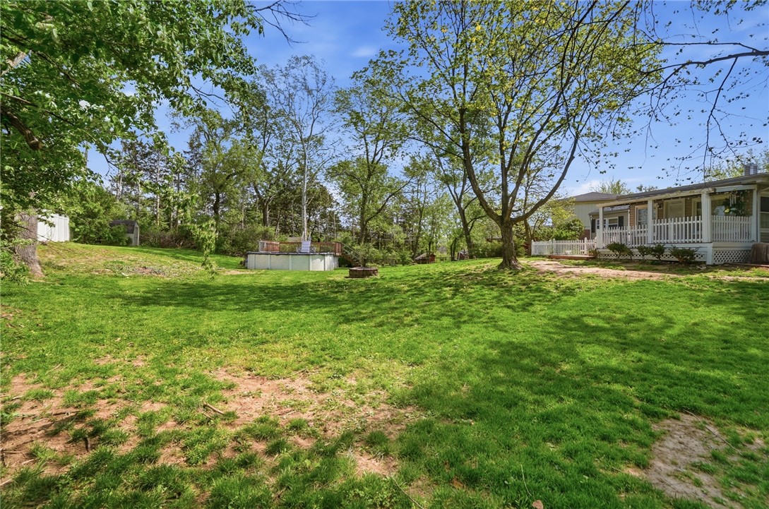 Spacious tree-lined backyard with a lawn, small above-ground pool, and raised deck.