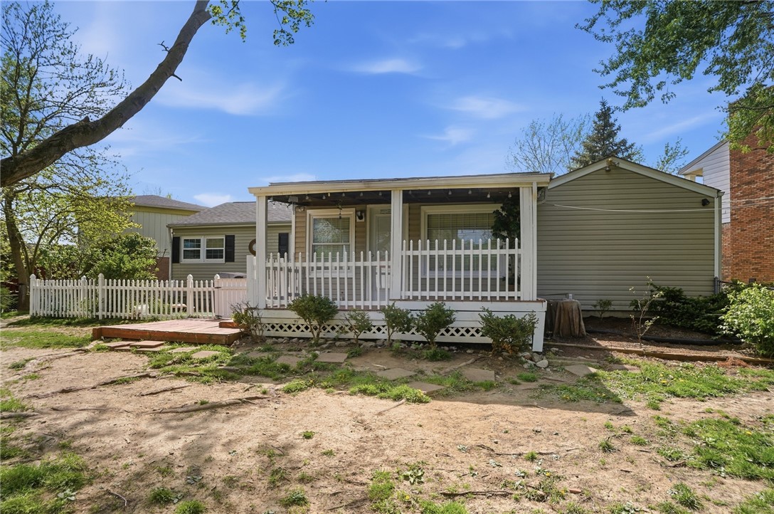 Home’s rear exterior with a covered porch, white railings, and a fenced yard.