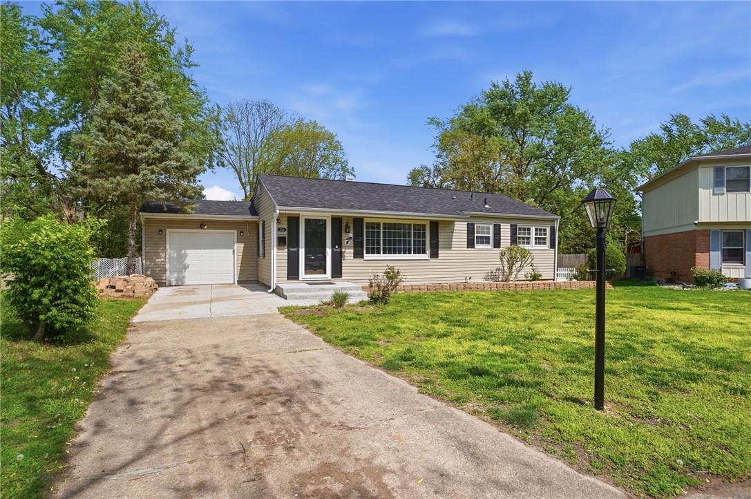 Single-story beige house with an attached garage, driveway, and broad front lawn.
