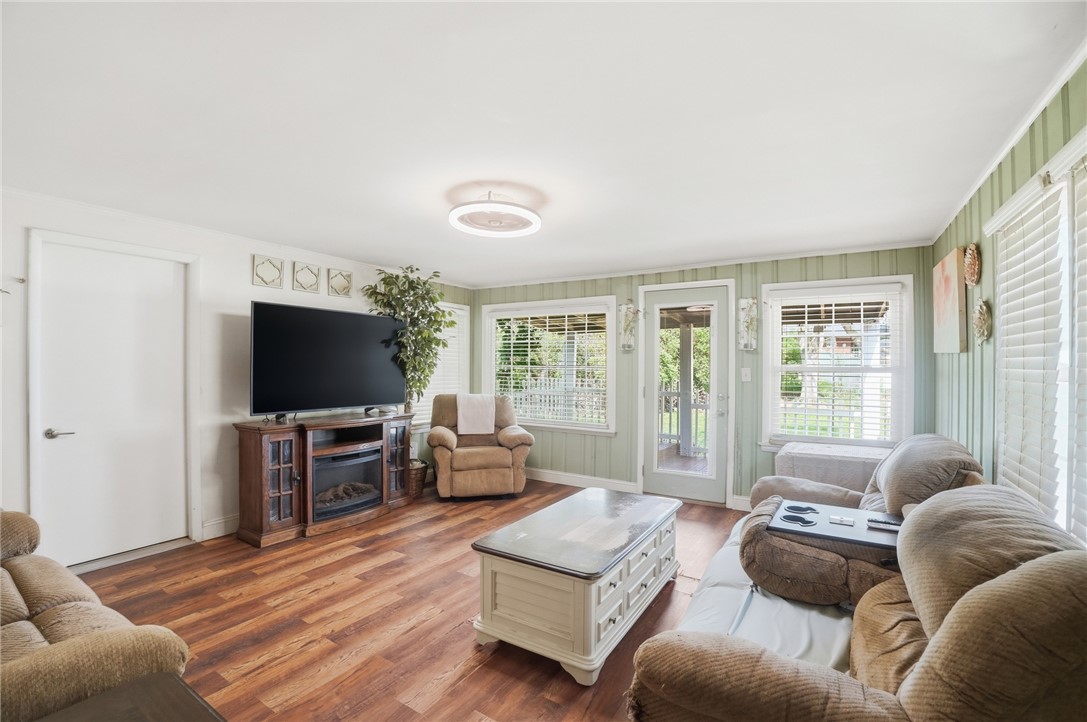 Furnished living room with green striped walls, wood floors, and a glass door opening to the outside.