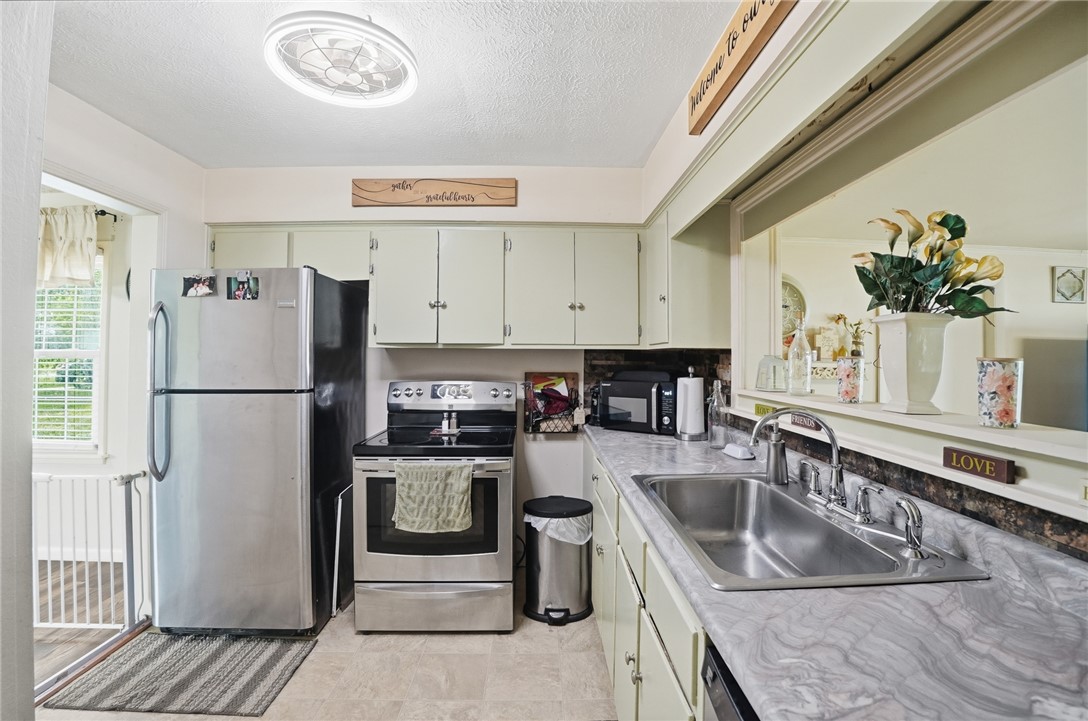 Kitchen with stainless steel appliances, white cabinets, and a long counter with a double-basin sink.