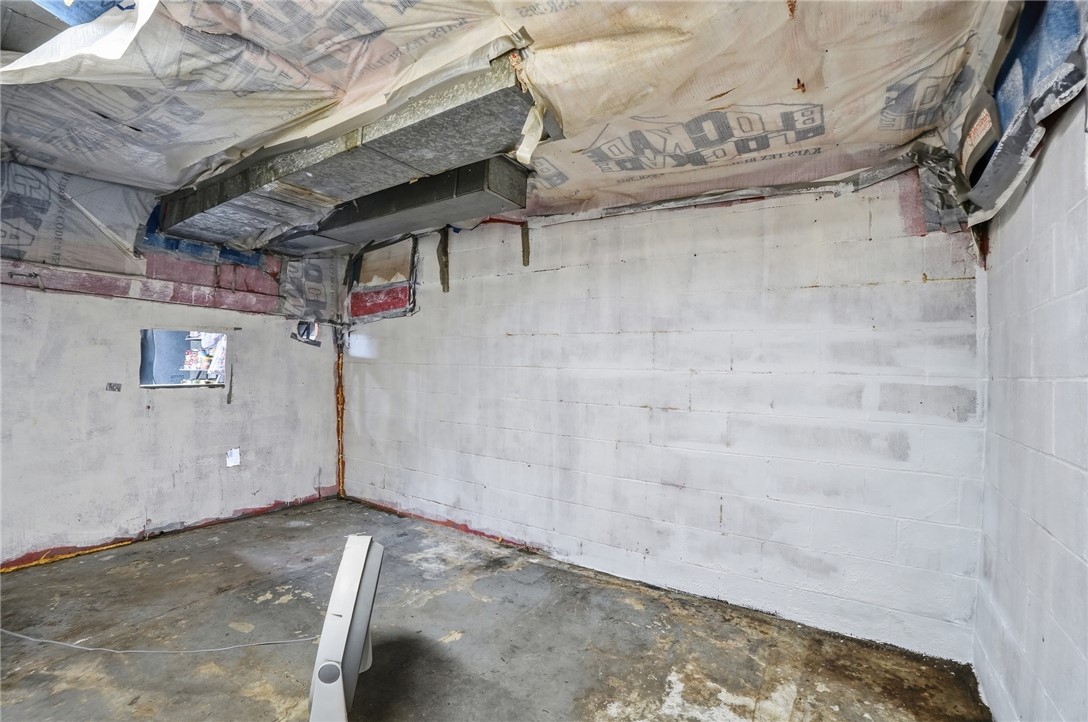 Unfinished basement with exposed ceiling insulation, ductwork, and a concrete floor.