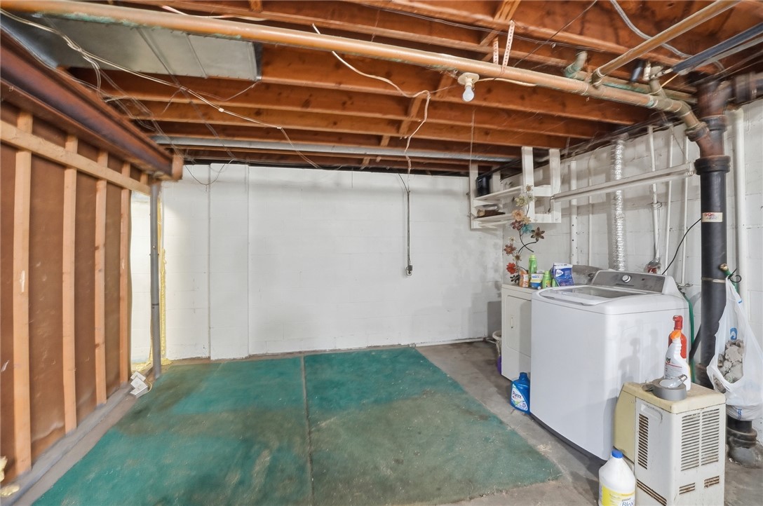 Unfinished basement laundry area with a washer, dryer, exposed joists, and painted concrete floor.