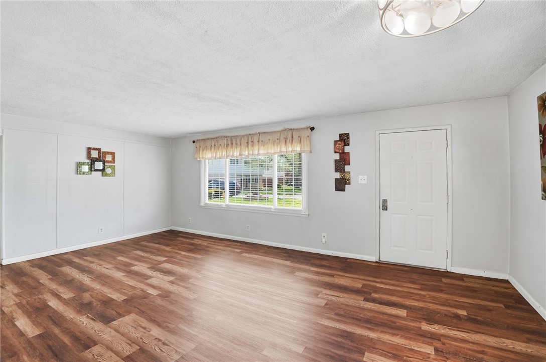 Unfurnished living room with dark wood-look flooring and a large window.