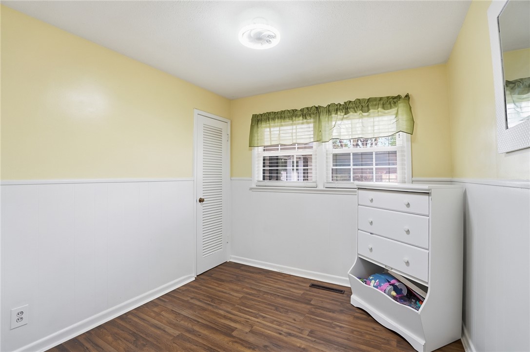 Bedroom with yellow walls, white wainscoting, two windows, and a white dresser.
