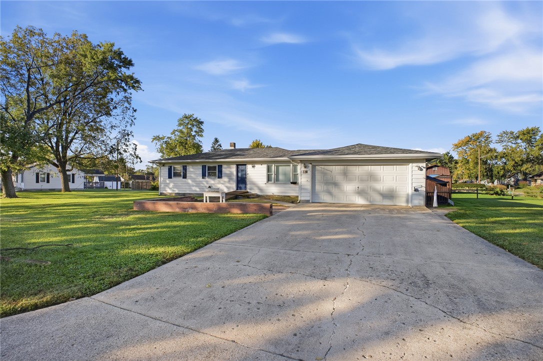 Single-story house with a two-car garage, broad concrete driveway, and spacious lawn.