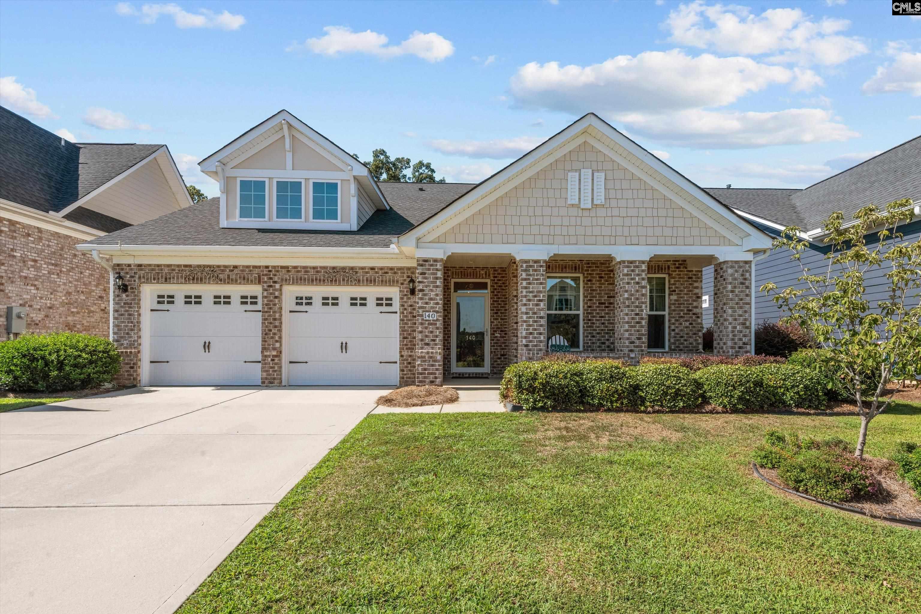 Brick home with a two-car garage, covered entry, and neatly trimmed hedges.