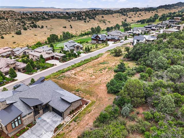 Aerial view of a gray-roofed home beside open scrubland at the edge of a neighborhood.