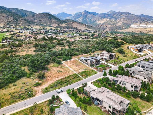 Vacant lot beside a residential road, with nearby homes and mountain views.