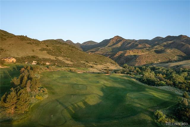 Aerial view of a green fairway bordered by foothills and distant mountain ridges.