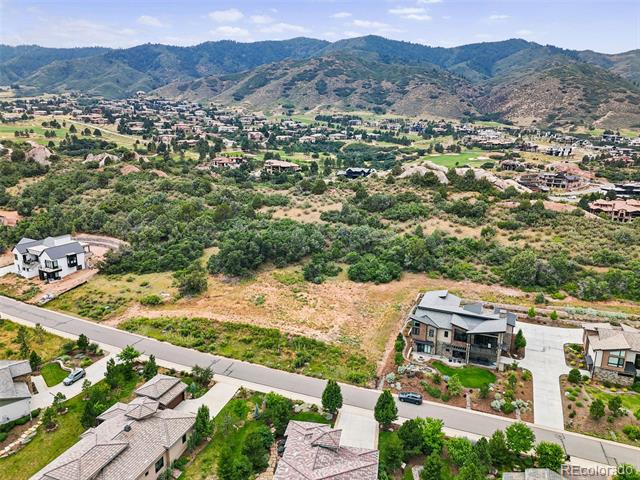Aerial view of a vacant parcel among homes, with foothills and mountains beyond.