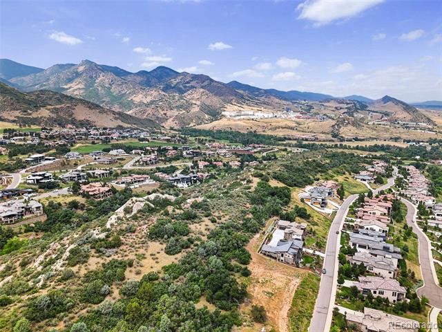 Aerial view of hillside homes and winding roads below a mountain range.