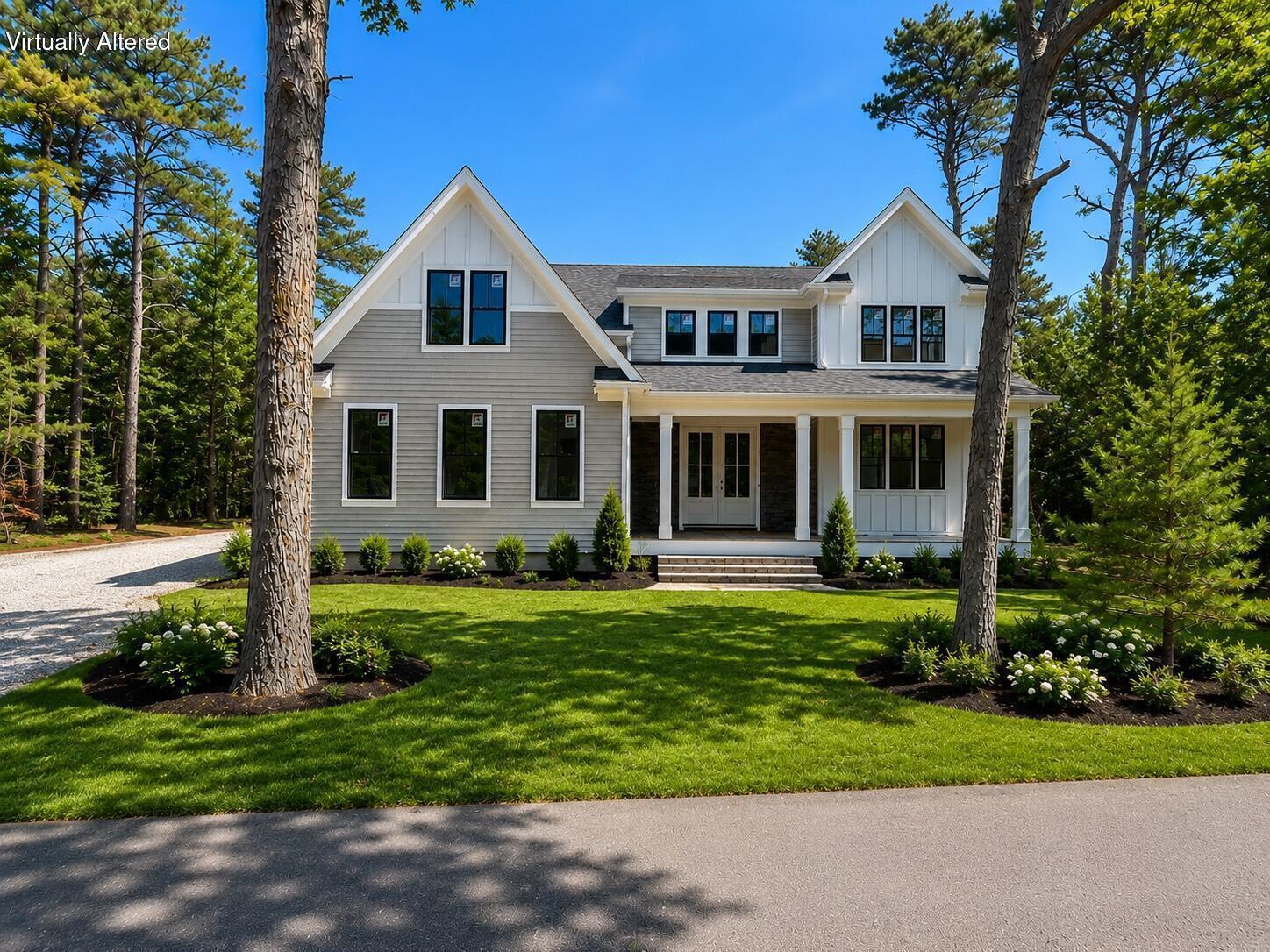 Gray-and-white two-story home with front gables and a covered porch, framed by pine trees.