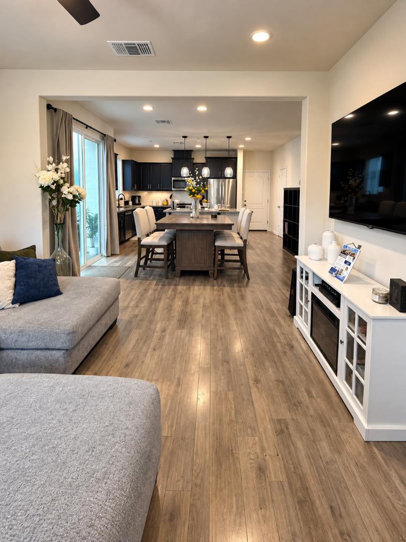 Open-plan living room and kitchen with gray sectional, dark cabinets, and a dining island.