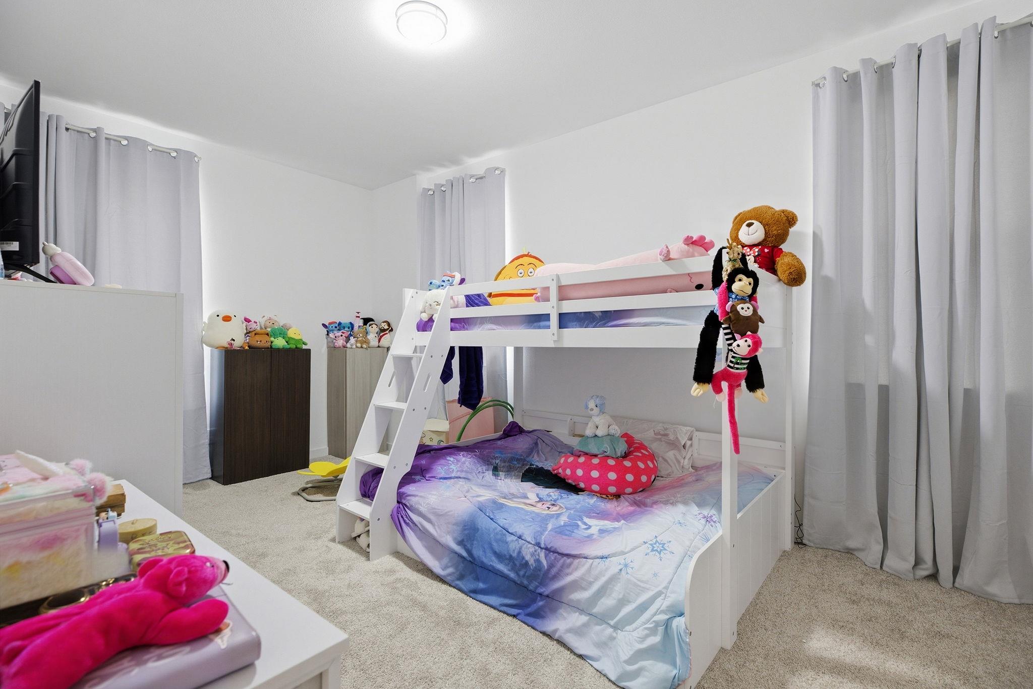Child's bedroom with a white bunk bed, colorful bedding, and plush toys.