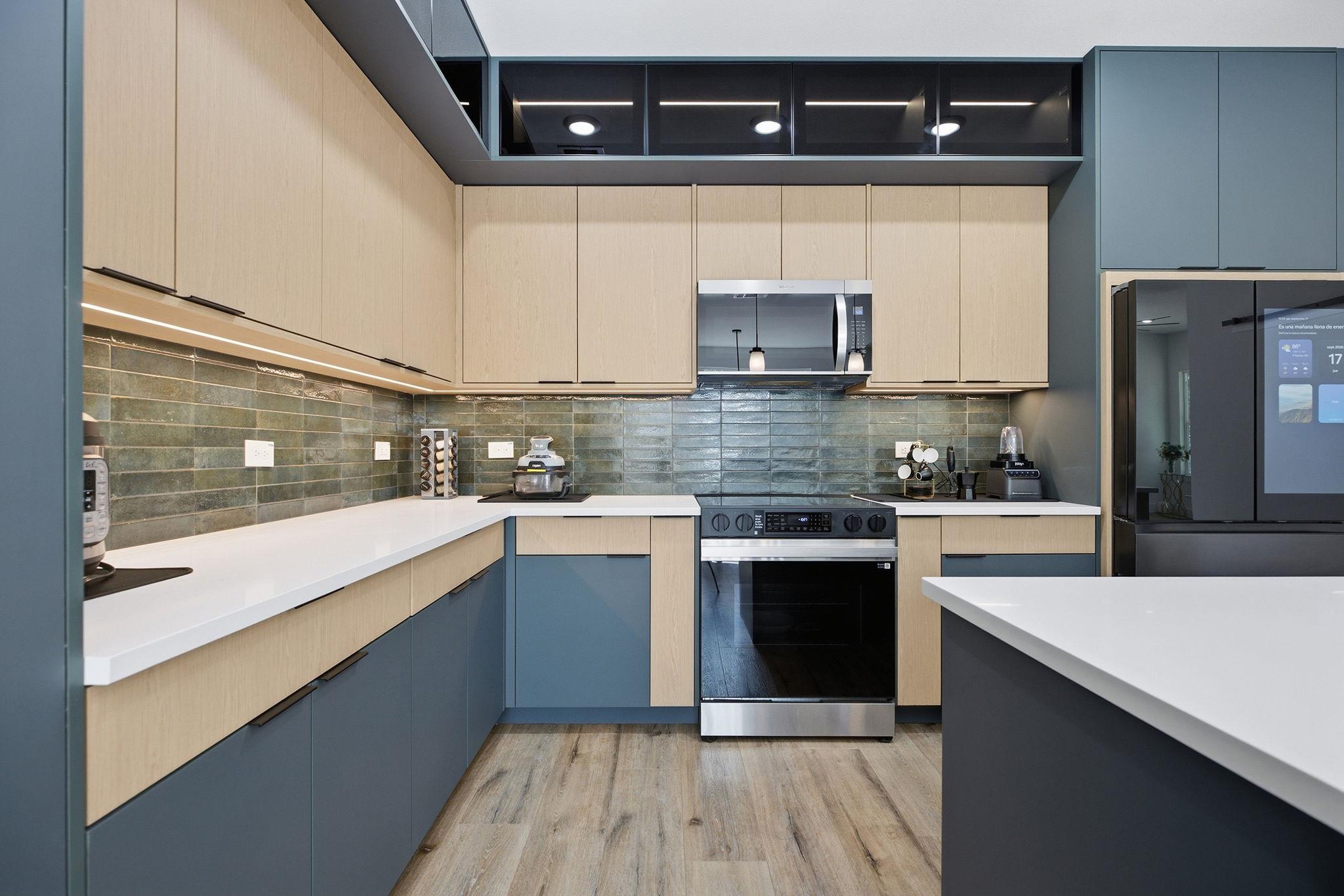 Modern kitchen with blue lower cabinets, light wood cabinetry, and stainless steel appliances.