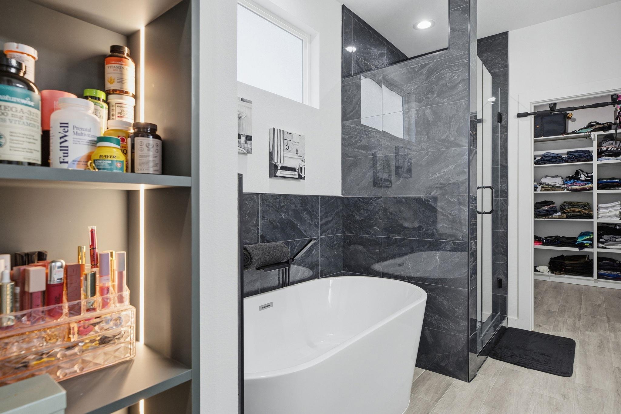 Modern bathroom with a freestanding tub, dark tiled shower, and adjoining walk-in closet.