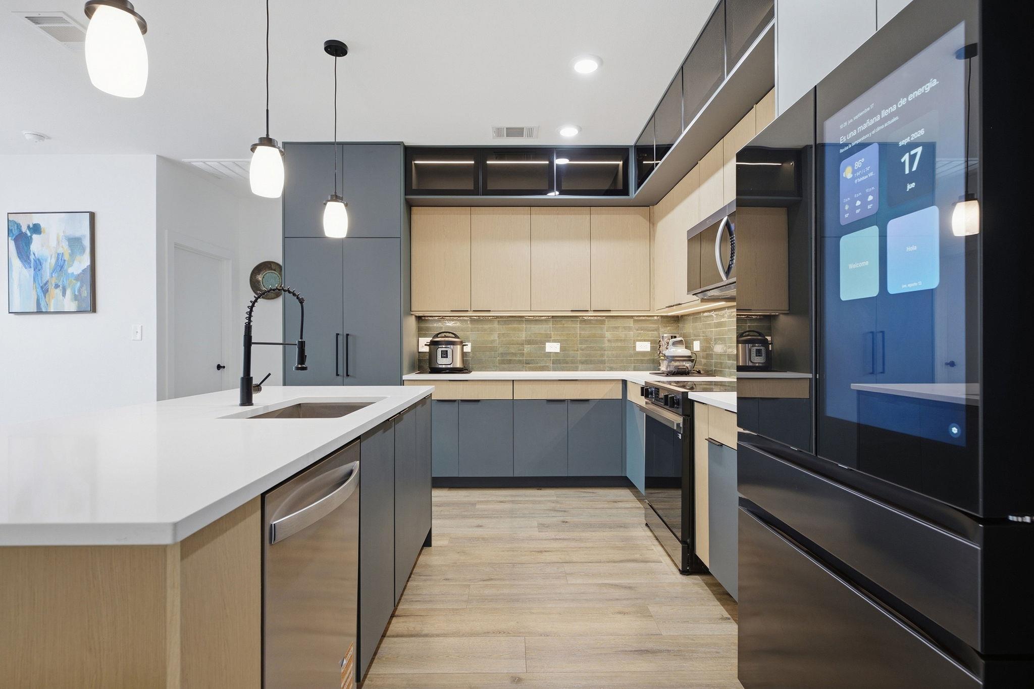 Modern kitchen with a white island, two-tone cabinetry, and a large smart refrigerator.