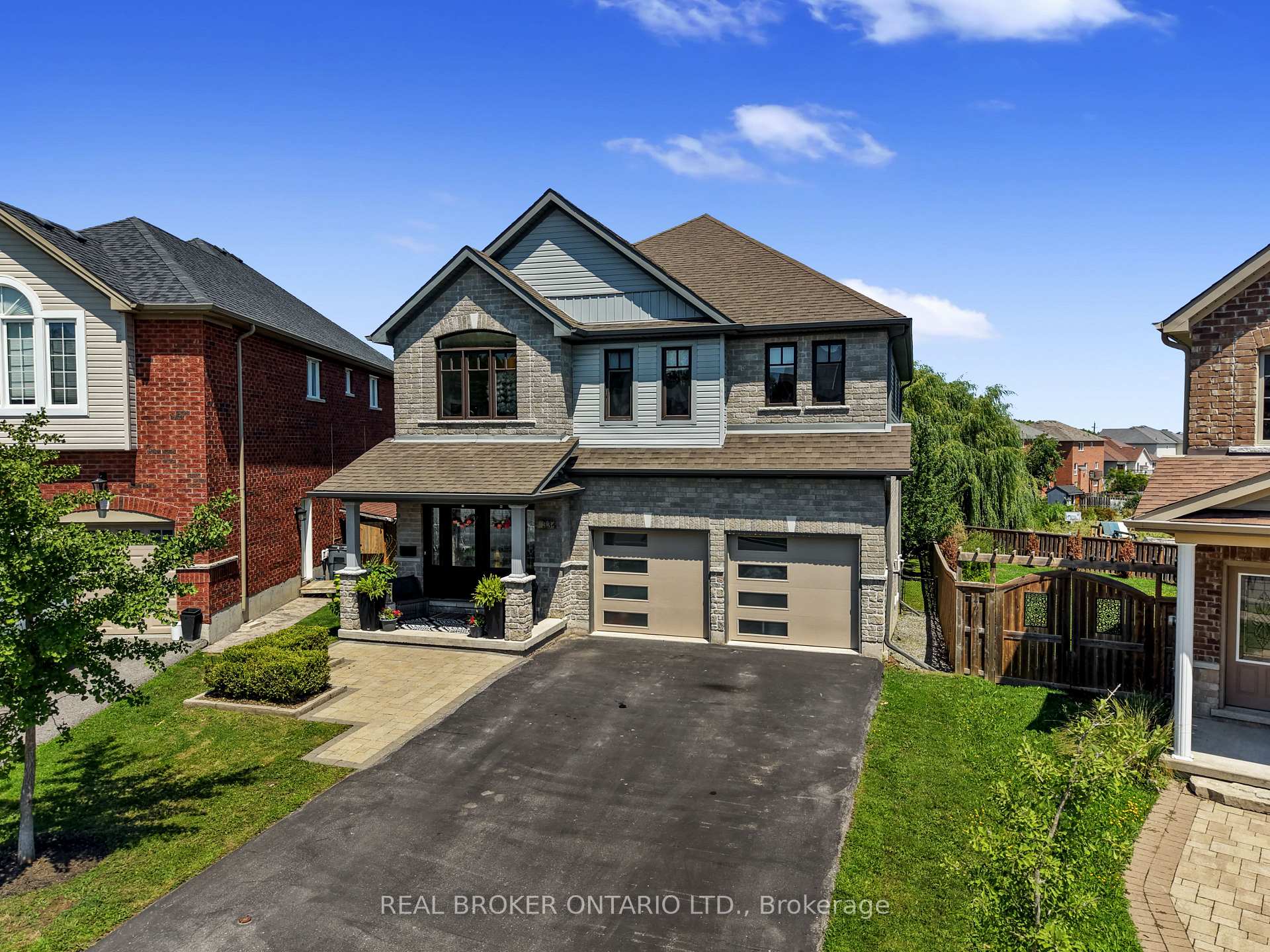 Two-storey stone-and-siding home with a covered porch, double garage, and paved driveway.