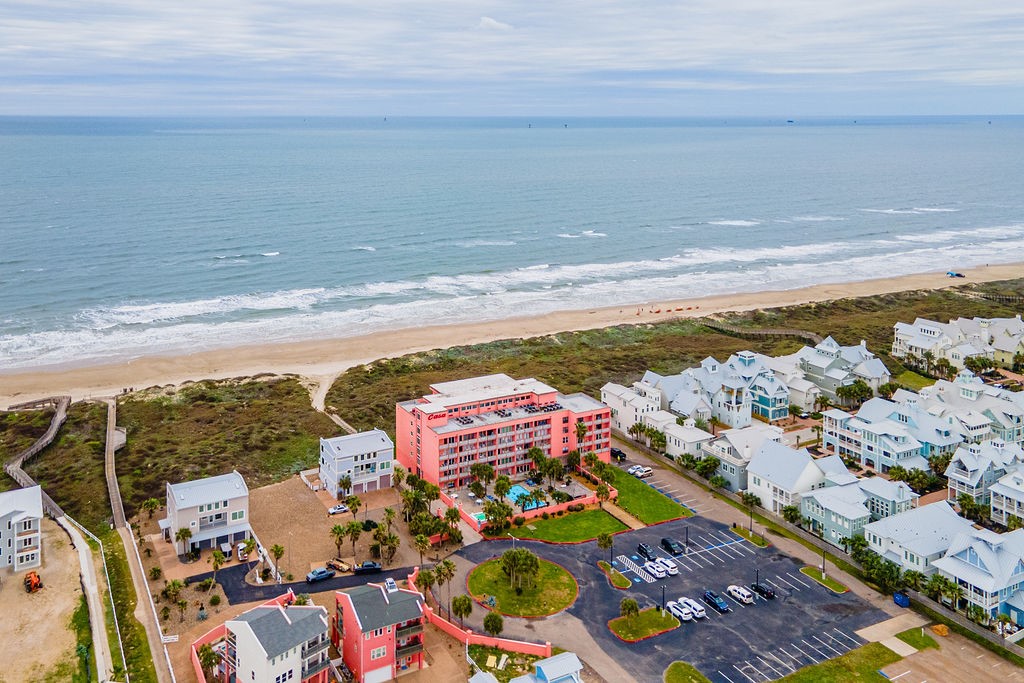 Coastal condominium and nearby homes beside a sandy beach and the Gulf of Mexico.