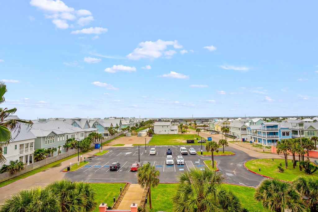 Residential community with a parking lot, palm trees, and rows of coastal-style homes.