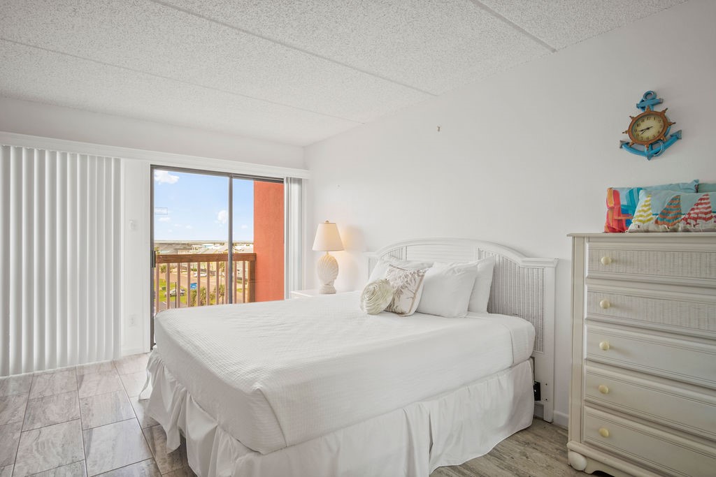 Bedroom with a white bed and sliding glass door opening onto a balcony.