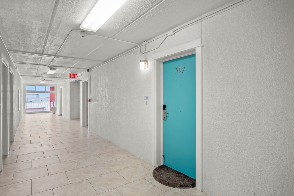 Hallway leading to turquoise unit 509 door, with an EXIT sign at the far end.