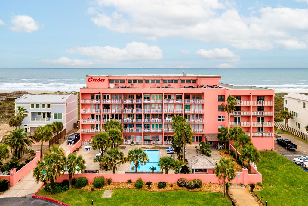 Pink Casa condominium with balconies and a pool, facing the ocean.