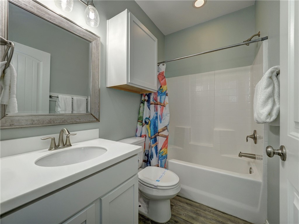 Bathroom with a white vanity, framed mirror, and bathtub with a colorful shower curtain.