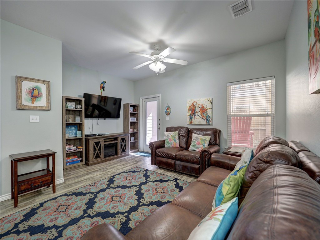 Living room with brown leather sofas, a colorful patterned rug, and bird artwork.