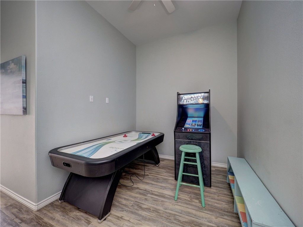 Game room with an air hockey table, arcade cabinet, and mint-green stool.