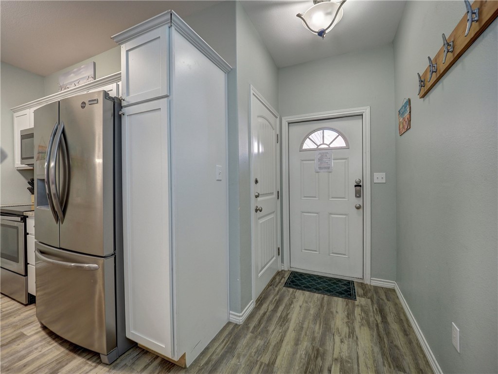 Entryway with a white front door and semicircular window beside a stainless-steel refrigerator.