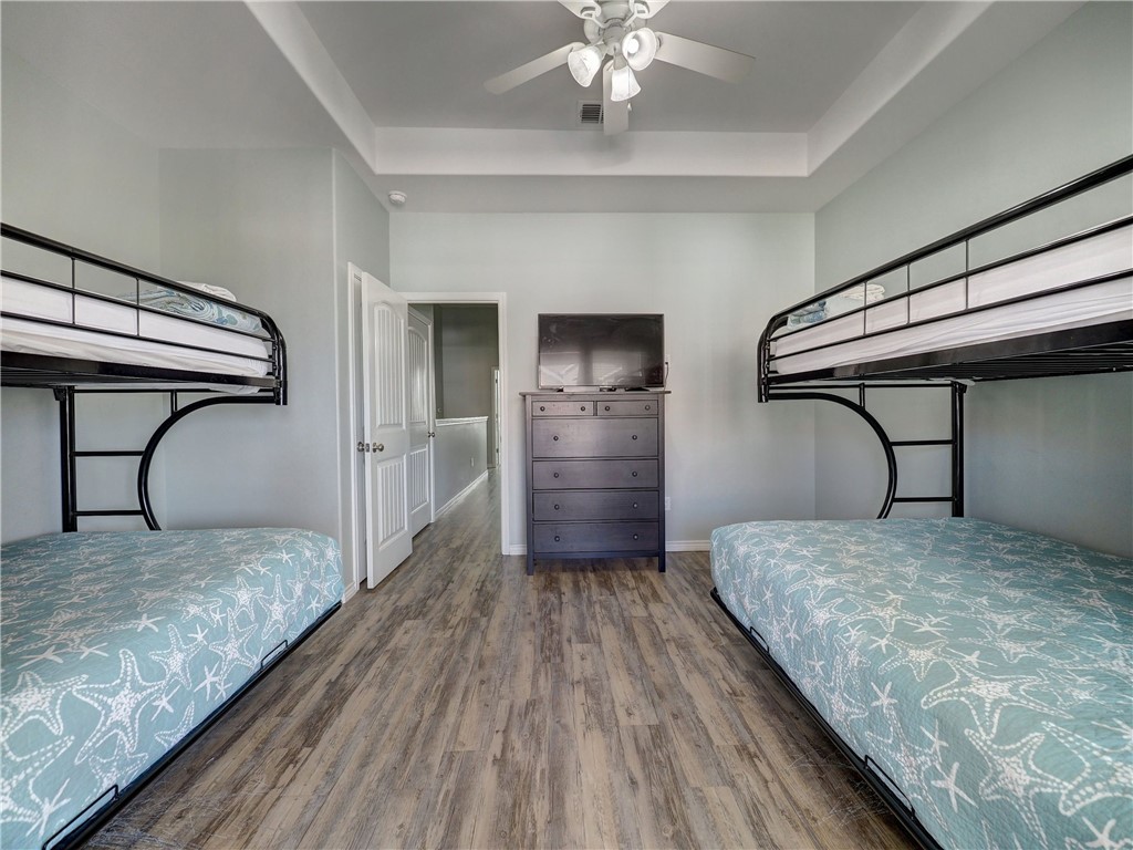 Bedroom with matching bunk beds, starfish-patterned bedding, and a dresser with television.
